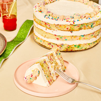 A festive dessert table with a 10 inch birthday cake next to a small plate with a birthday cake slice