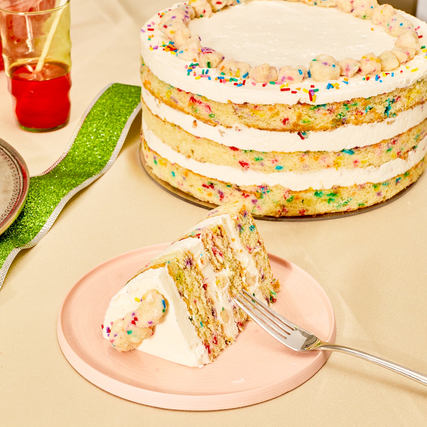 A festive dessert table with a 10 inch birthday cake next to a small plate with a birthday cake slice