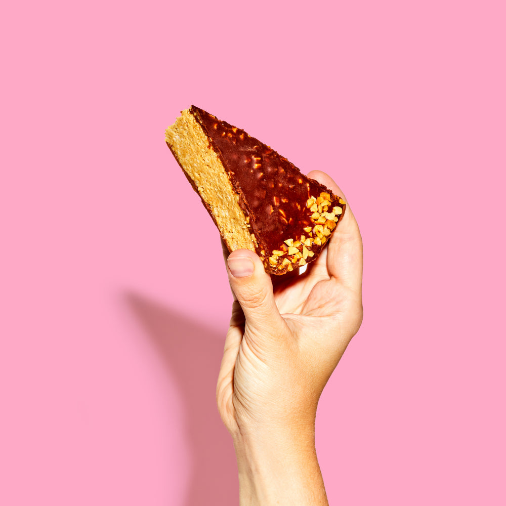 A person holding up a slice of limited-edition Chocolate Peanut Butter Crunch Pie