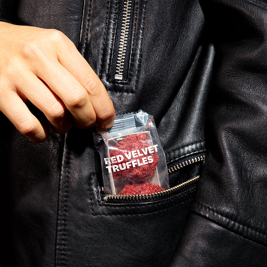A close up view of the pocket on a jacket with a 3-pack of red velvet cheesecake truffles nestled inside