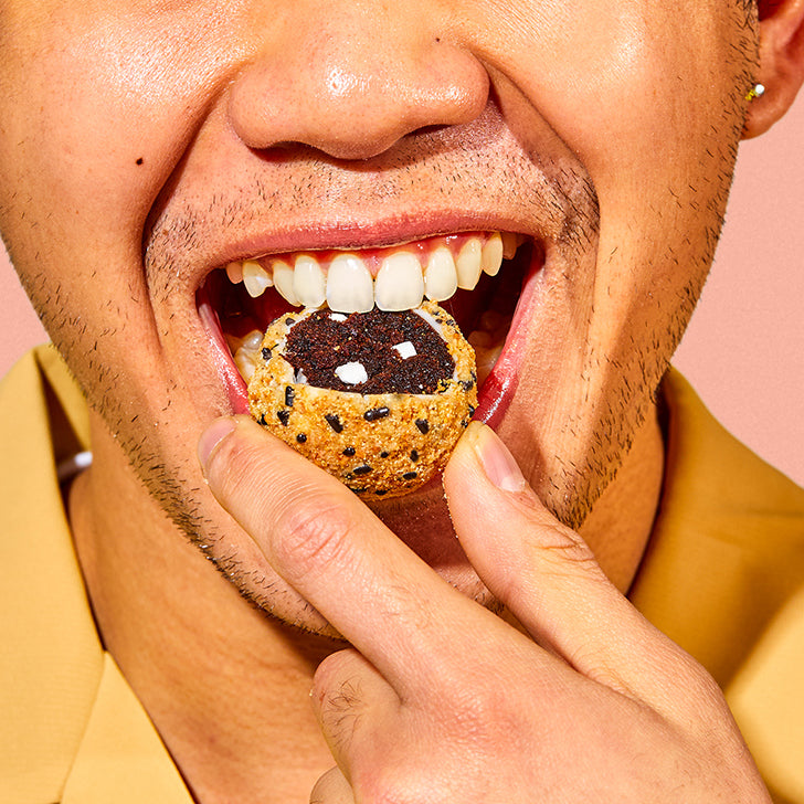 close up view of a person's face while taking a bite into a s'mores cake truffle