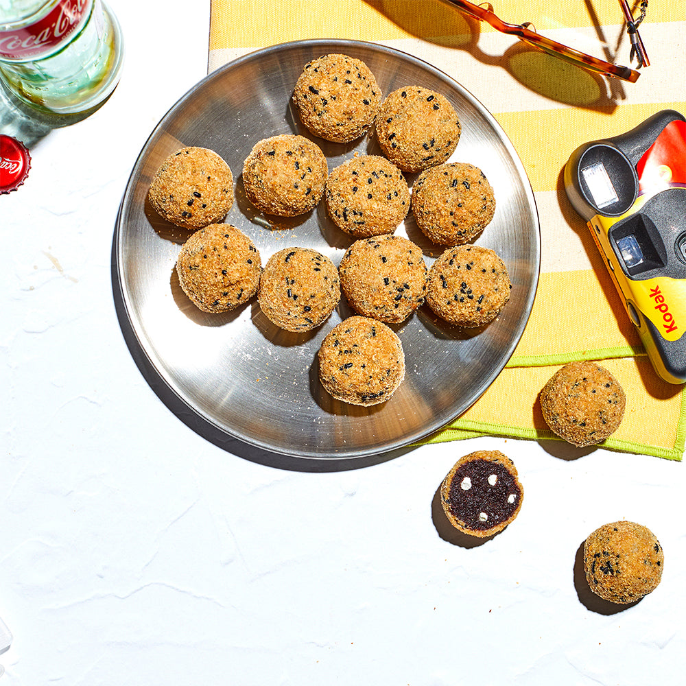 overhead view of a plate of s'mores cake truffles on an outdoor table in the sun, surrounded by sunglasses, a kodak disposable camera, and an empty glass bottle of coca-cola.